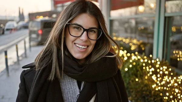 在欧洲的一个城市里 一个戴着眼镜 面带微笑的黑发女人正在享受都市冬夜的灯火 — 图库照片