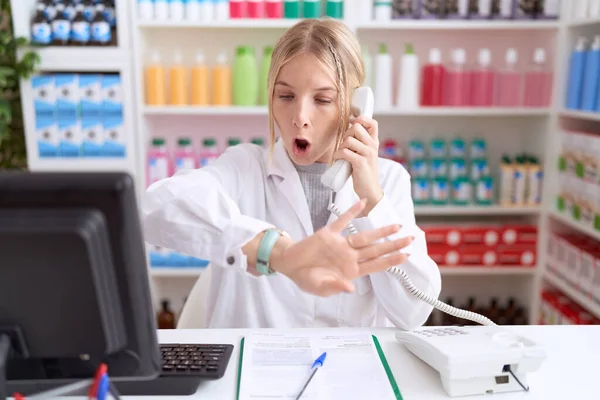 Young Caucasian Woman Working Pharmacy Drugstore Speaking Telephone Looking Watch — Stock Photo, Image