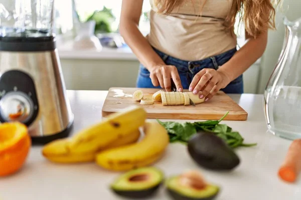 年轻美丽的恐慌女人在厨房用搅拌机切香蕉准备蔬菜冰沙 — 图库照片