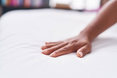 Yatak odasında çarşafa dokunan Afrikalı Amerikalı kadın.