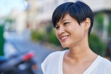 Middle age chinese woman smiling confident looking to the side at street