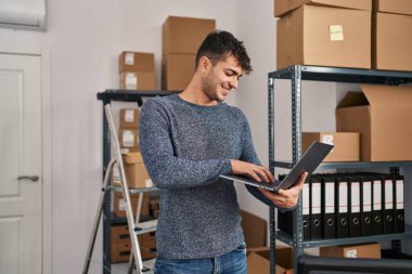 Ofiste dizüstü bilgisayar kullanan Latin asıllı genç bir iş adamı.