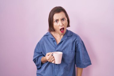 Orta yaşlı İspanyol kadın şok olmuş bir şekilde kahve içiyor. Şüpheci ve alaycı görünüyor. 
