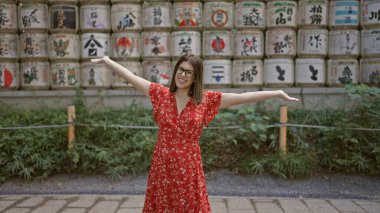 Neşeli İspanyol kadın, gözlüklü esmer, Tokyo kültürünü kucaklıyor, Meiji tapınağında kollarını açıp gülümsüyor, özgürlüğün tadını çıkarıyor, genç yetişkin hayatının başarısı, etrafa bakarken