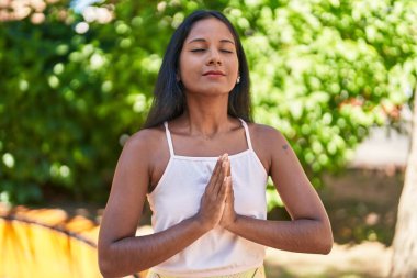 Genç ve güzel bir kadın parkta yoga egzersizi yapıyor.