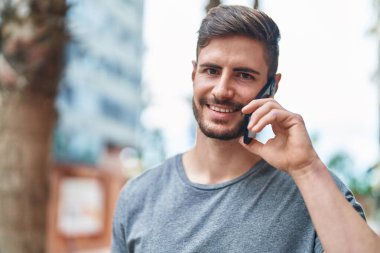 Kafkasyalı genç adam gülümsüyor. Kendine güvenen caddedeki akıllı telefondan konuşuyor.