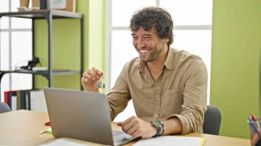 Genç İspanyol emlakçı. Elinde yeni evin anahtarı var. Ofiste çalışıyor.