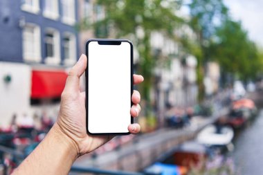 Elinde akıllı telefon tutan adam Amsterdam 'da beyaz boş ekran gösteriyor.