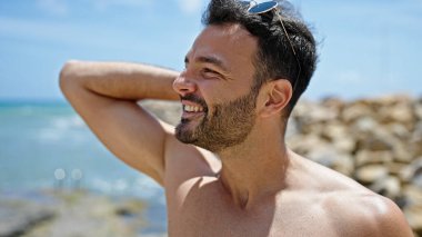 Genç İspanyol turist, kumsalda elleri çıplak saçlarını tarıyor.