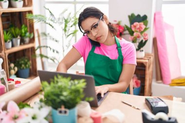 Çiçekçide dizüstü bilgisayar kullanarak konuşan İspanyol bir çiçekçi kadın.