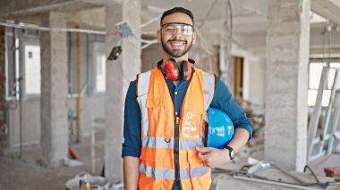 İnşaat alanında kendine güvenen genç İspanyol mimar gülümsüyor.