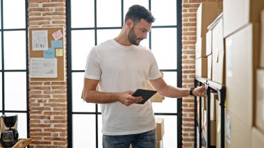 Latin kökenli genç bir iş adamı ofiste dokunmatik ped kullanıyor.