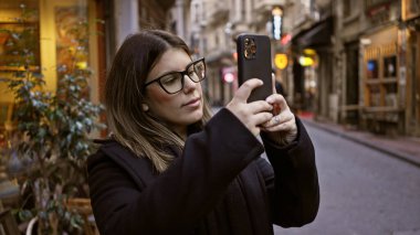 İstanbul Caddesi 'nde akıllı telefon kullanan genç kadın, Türkiye' de seyahat, kentsel ve turizm temaları sergiliyor.