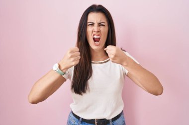 Genç esmer kadın, öfkeyle bağırırken kızgın ve kızgın yumruklar sallıyor. öfke ve agresif konsept. 