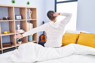 Genç İspanyol adam yatak odasında kollarını gererek uyanıyor.