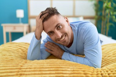 Genç İspanyol adam yatakta kendinden emin bir şekilde gülümsüyor.