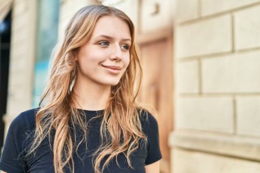 Young blonde woman smiling confident looking to the side at street
