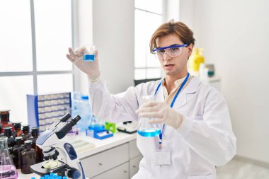 Kafkasyalı genç bilim adamı laboratuarda test tüpleri tutuyor.