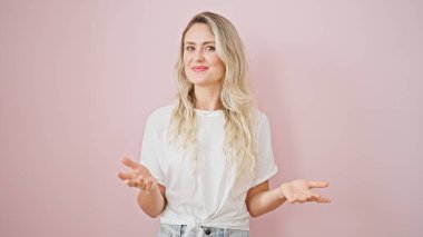 Genç sarışın kadın gülümsüyor. Kendinden emin, soyutlanmış pembe arka planda konuşuyor.