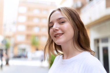 Sokakta kendine güvenen beyaz kadın gülümsüyor.