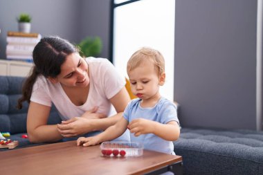 Anne ve oğlu evde ahududu yerken kendinden emin bir şekilde gülümsüyor.