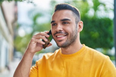 Genç İspanyol adam gülümsüyor. Kendine güveniyor. Sokakta akıllı telefondan konuşuyor.