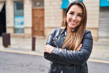 Sokakta kollarını kavuşturmuş genç, güzel İspanyol bir kadın.