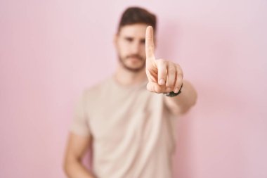 Pembe arka planda duran İspanyol sakallı adam parmağını kaldırmış ve kızgın bir ifadeyle işaret ediyor, hiçbir hareket göstermiyor. 