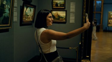 Güzel İspanyol bir kadın sanat galerisini ziyaret ediyor. Viyana 'daki sanat müzesinde selfie çekiyor.