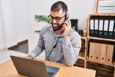 Ofiste çalışırken gülümseyen İspanyol bir çağrı merkezi ajanı.