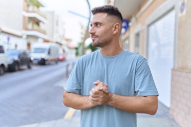 Latin kökenli genç adam ciddi bir ifadeyle sokağa bakıyor.