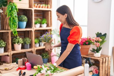 Çiçekçide dizüstü bilgisayar kullanan güzel İspanyol bir çiçekçi kadın.
