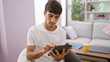 Genç İspanyol adam evde dokunmatik ped kullanıyor.