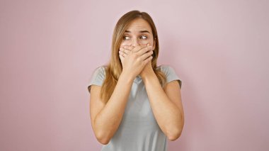 Vay canına! Neşeli genç sarışın kadın, şaşkın, elleri ağızlı, pembe izole edilmiş arka planda duran. Mutlu sürprizin güzel ifadesi!