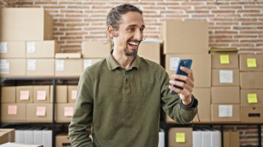 Ofisteki akıllı telefonu kullanan Latin asıllı genç bir iş adamı.