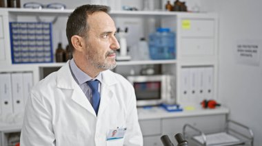 Gri saçlı, ciddi bir orta yaşlı adam, çalışkan bir bilim adamı, tıp bilimi ve teknolojinin ruhunu somutlaştıran, laboratuarda son teknoloji araştırmalarına dalmış.?