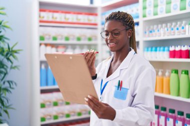 Afrika kökenli Amerikalı kadın eczacı eczanede akıllı telefondan kitap okuyor.