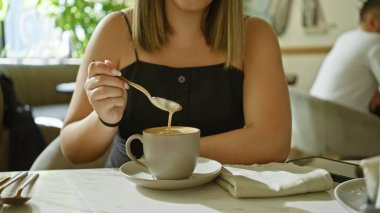 Rahat bir kafe ortamında kahve içen genç bir kadın rahat ve rahat bir yaşam tarzını somutlaştırıyor..