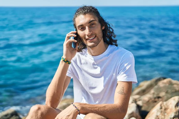 Young Hispanic Man Talking Smartphone Sitting Rock Seaside — Stock Photo, Image