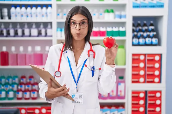 Brunette Young Woman Working Pharmacy Drugstore Holding Red Heart Puffing — Stock Photo, Image
