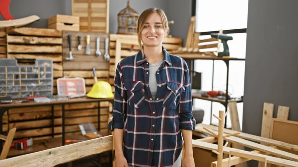Young blonde woman carpenter smiling confident standing at carpentry