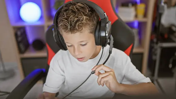 Blond boy streamer playing video game using computer at gaming room