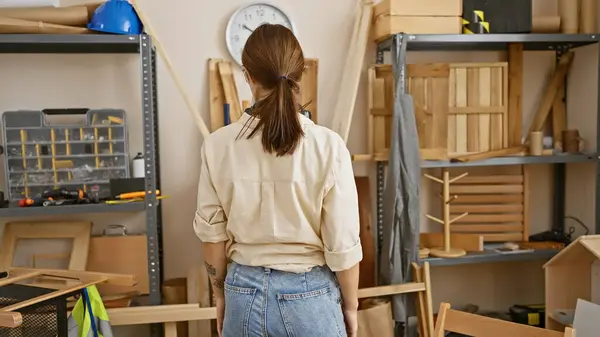 在一间设备齐全的木工车间里 一个年轻女子若有所思地站在那里的背影 — 图库照片