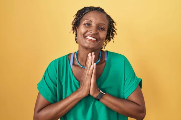 Африканская Женщина Дредами Стоящая Желтом Фоне Молясь Руками Вместе Просит — стоковое фото