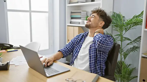 劳累过度的Arab商人在办公室里饱受颈痛之苦 疲惫的年轻工人在笔记本电脑上边上网边工作边紧张 — 图库照片