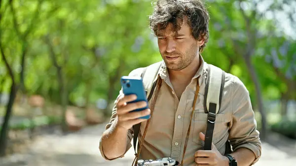 Νεαρός Ισπανόφωνος Τουρίστας Φορώντας Σακίδιο Χρησιμοποιώντας Smartphone Στο Πάρκο — Φωτογραφία Αρχείου