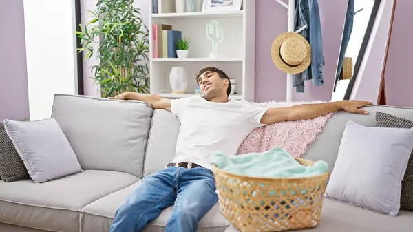 Young hispanic man relaxed on sofa at home