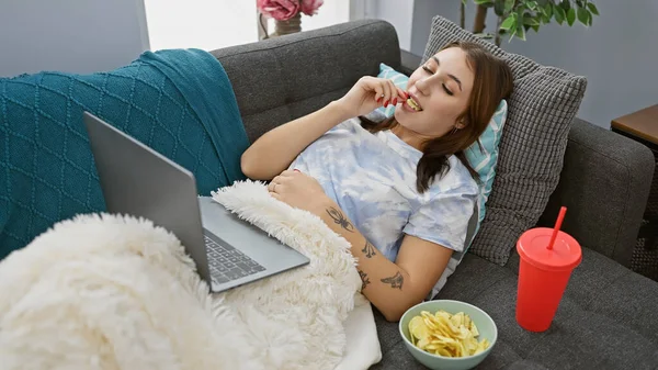 Relaxed Caucasian Woman Enjoys Snacking While Using Laptop Sofa Cozy — Stock Photo, Image