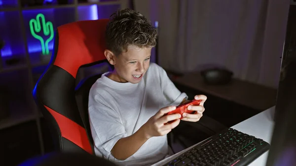 Adorable blond boy streamer confidently playing a futuristic video game, smartphone in hand, streaming live from a cozy gaming room in the heart of the night.