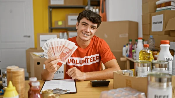 Smiling Young Hispanic Teenager Joyfully Volunteers Charity Center Confidently Holding — Stock Photo, Image